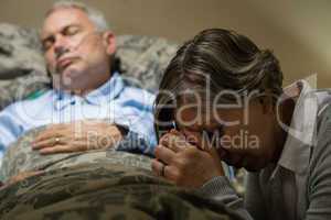 Uneasy senior woman praying for sick man