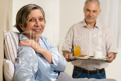 Caring senior man bringing breakfast to wife