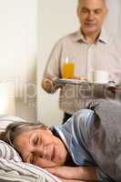 Loving senior husband serving breakfast to wife