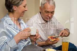 Elderly couple eating romantic breakfast in bed