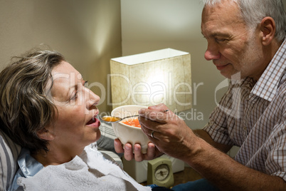 Loving retired husband feeding his ill wife