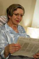 Relaxed smiling mature woman reading newspaper