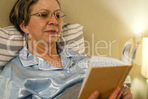 Aged woman reading book in residential home
