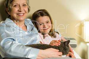 Cheerful senior woman with granddaughter and cat
