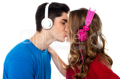 Young couple enjoying music and kissing