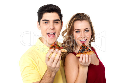 Couple posing with pizza slice, about to eat