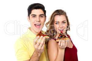 Couple posing with pizza slice, about to eat