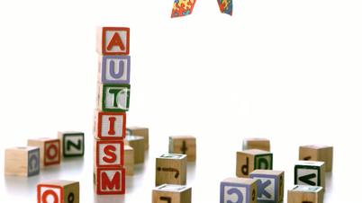 Autism ribbon falling beside blocks spelling autism