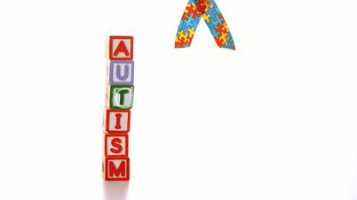 Awareness ribbon falling beside blocks spelling autism