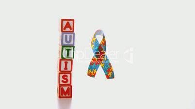Awareness ribbon dropping beside blocks spelling autism