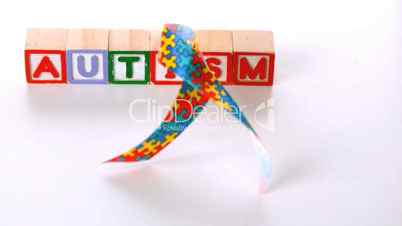 Awareness ribbon falling in front of autism letter blocks