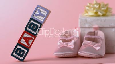 Baby blocks toppling over with booties and gift box in background