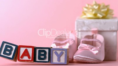 Baby blocks toppling over in front of booties and gift box