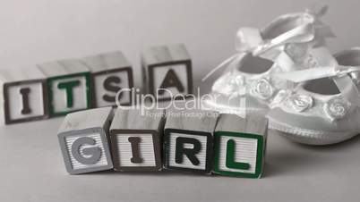 Its a girl message in letter blocks beside booties