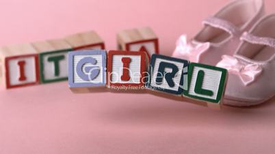 Its a girl message in letter blocks beside pink booties