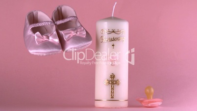 Baby shoes falling beside baptism candle and pacifier