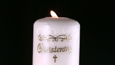 Lit christening candle flickering