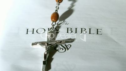 Rosary beads falling onto first page of bible