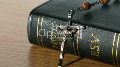 Rosary beads falling onto black bible