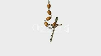 Rosary beads falling onto white surface