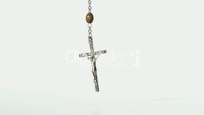Rosary beads falling onto a white surface