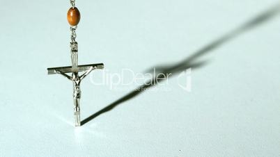 Rosary beads casting a shadow and then falling