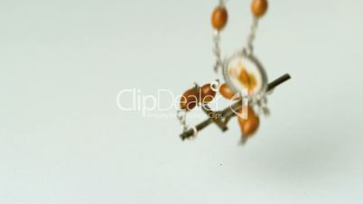 Rosary beads falling on white surface