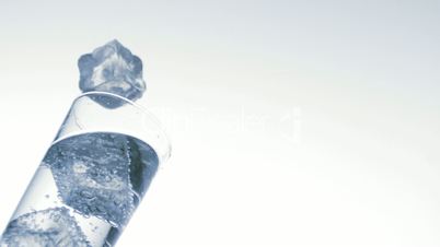Ice falling into glass of water