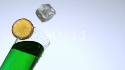Ice dropping into glass of green cocktail