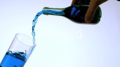 Blue liquid pouring into glass low angle