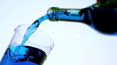 Blue liquid pouring into glass low angle close up