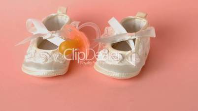 Pink soother falling onto baby shoes