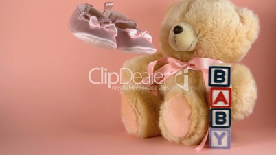 Baby shoes falling next to a teddy bear and baby blocks