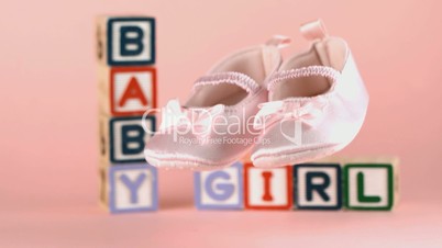 Baby shoes falling in front of baby blocks and soother