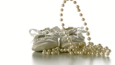 Pearl necklace falling onto baby shoes
