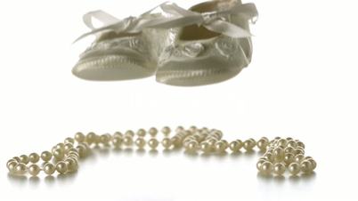 Baby shoes falling onto string of pearls