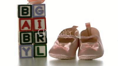 Yellow soother falling besides baby blocks and booties