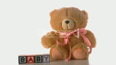 Teddy bear falling besides baby blocks