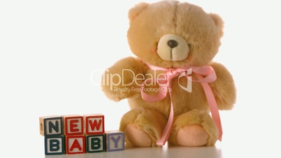 Cute teddy bear falling besides baby blocks