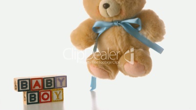 Fluffy teddy bear falling besides baby blocks