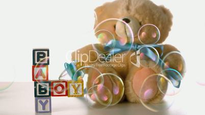 Bubbles floating over baby blocks soother and teddy bear