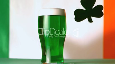 Large green shamrock falling beside pint of green beer