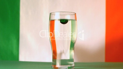 Irish flag mirrored through pint of water with green drop falling in