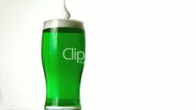 Foam pouring onto pint of green beer