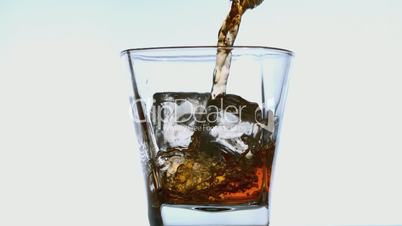 Whiskey pouring into tumbler with ice