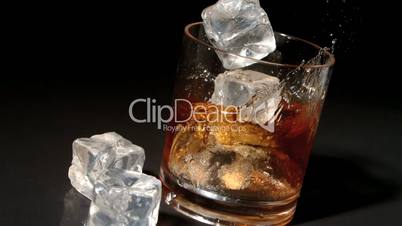 Ice cubes falling into tumbler of whiskey and ice