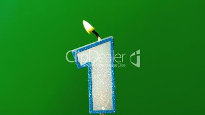 One birthday candle flickering and extinguishing on green background