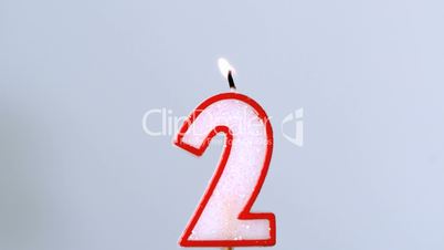 Two birthday candle flickering and extinguishing on blue background