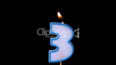 Three birthday candle flickering and extinguishing on black background