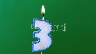 Three birthday candle flickering and extinguishing on green background